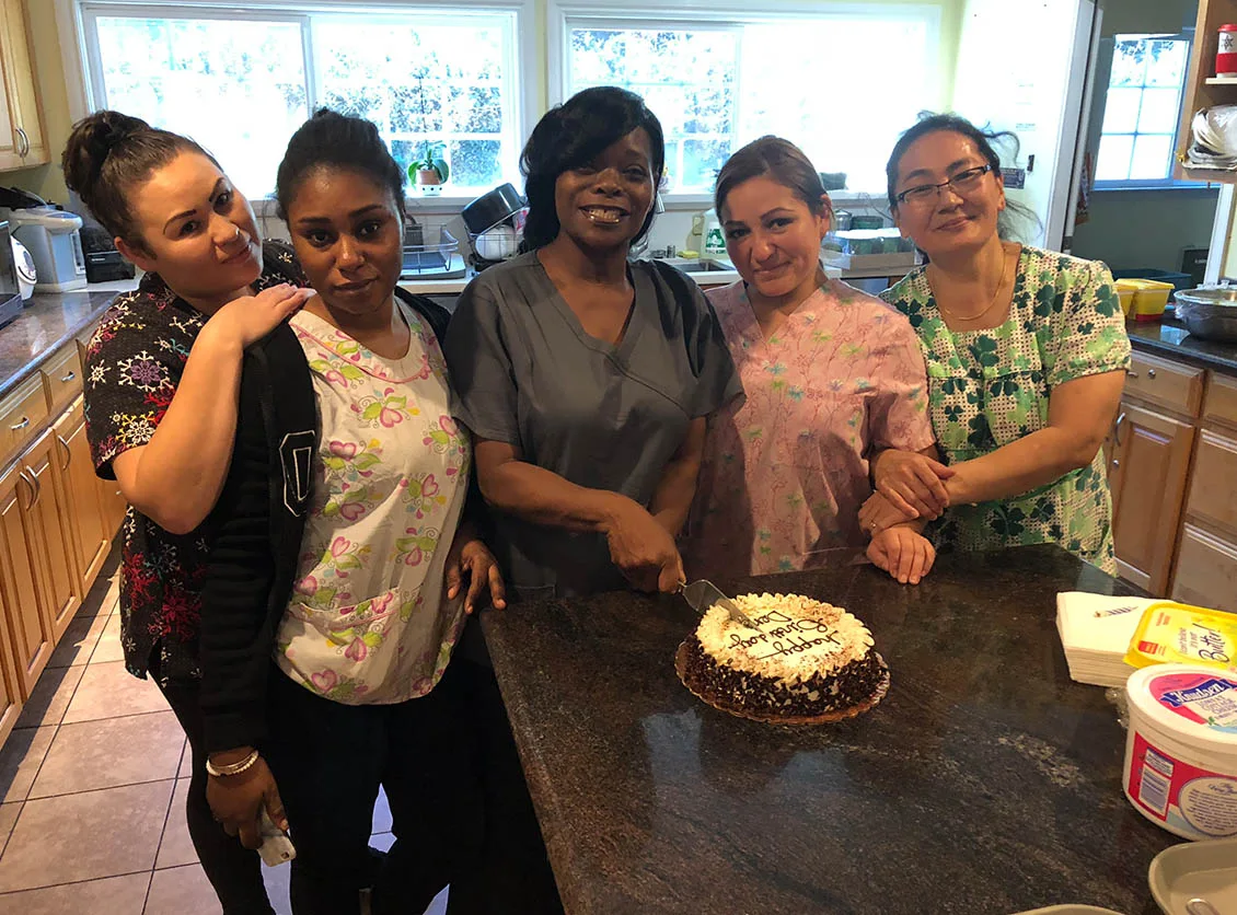 A group gathered around a celebration cake at Dimond Care